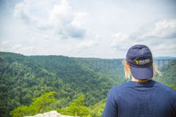 Female student looking from long point to New River Gorge Bridge