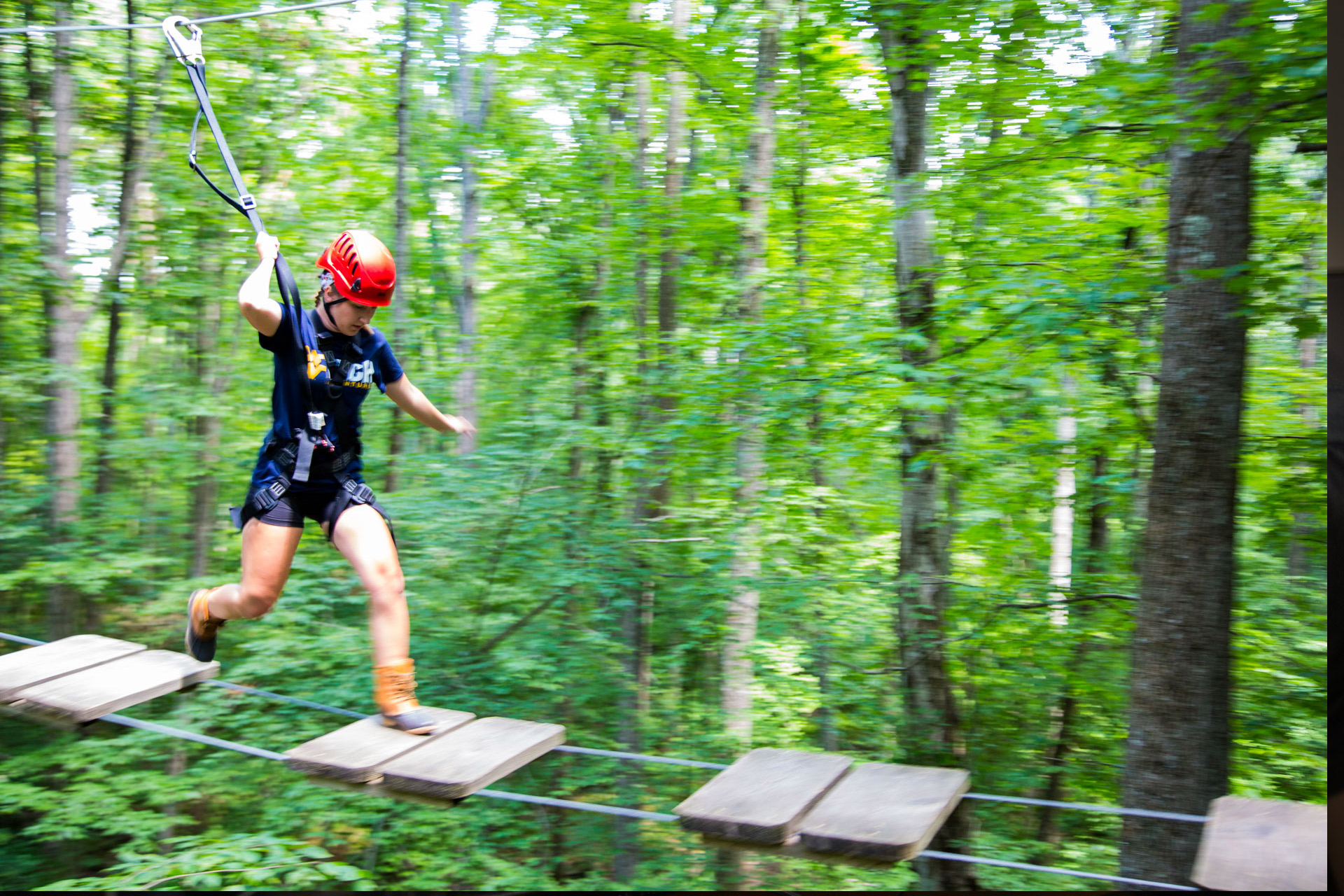 Woman moving across an open bridge on high ropes course
